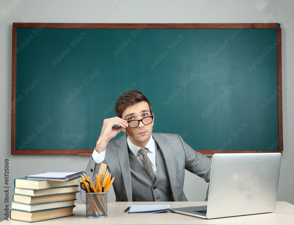 Young teacher sitting in school classroom