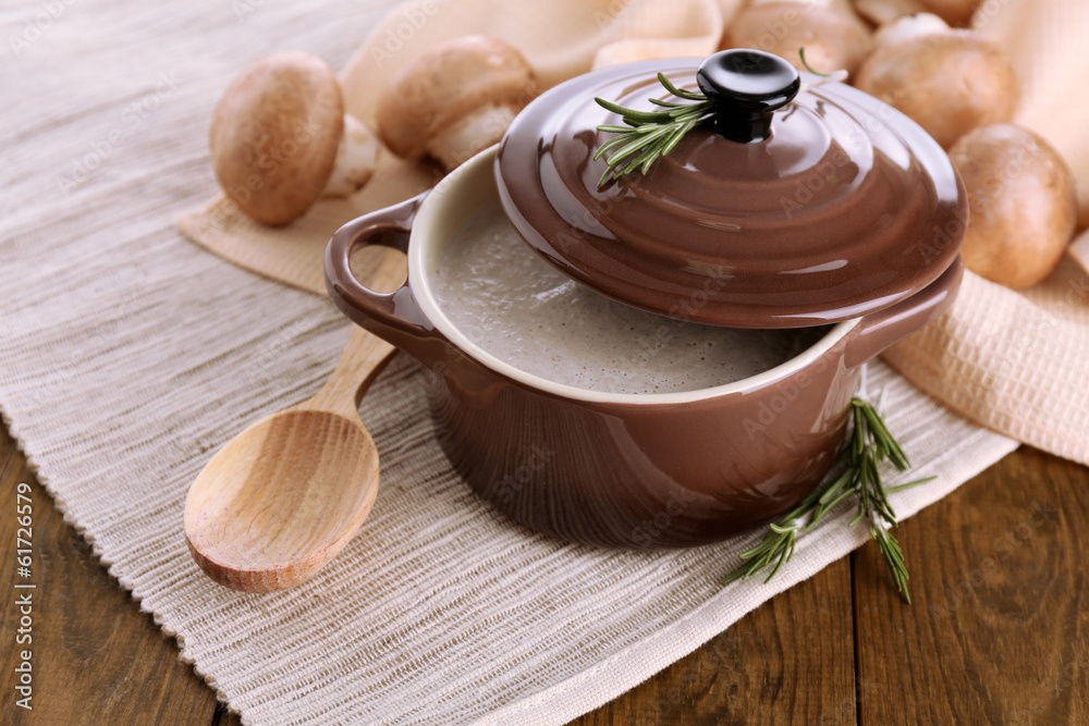 Mushroom soup in pot, on wooden background
