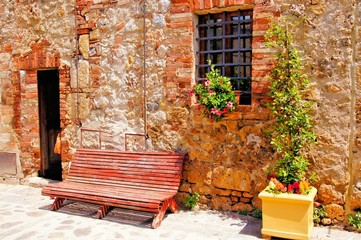 Fototapete - Bench along a medieval stone house in Tuscany, Italy