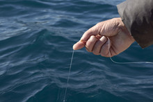 Man With Fishing Line In His Hand Catching Fish From The Boat