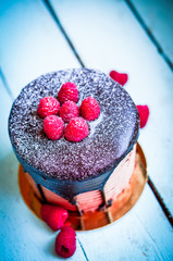 Wall Mural - Chocolate cake with raspberries on wooden background