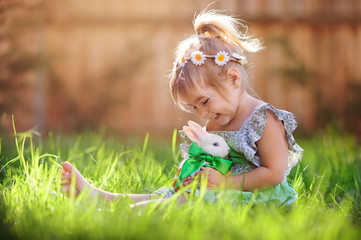 Cute little girl with a bunny rabbit has a easter at green grass