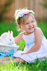 Cute little girl with a bunny rabbit has a easter at green grass