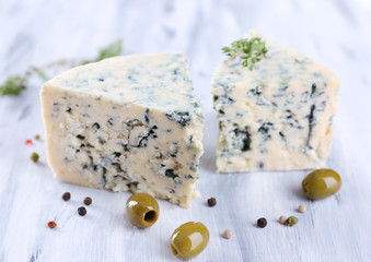 Tasty blue cheese with thyme and olives on wooden table