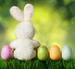 Wall Mural - Colorful easter eggs and rabbit on green grass over bokeh