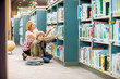 © Tyler Olson - Boy With Teacher Selecting Books From Bookshelf