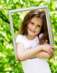 Wall Mural - little girl looking throgh wooden frame - beautiful nature backg