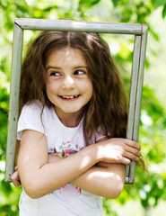 Wall Mural - little girl looking throgh wooden frame - beautiful nature backg