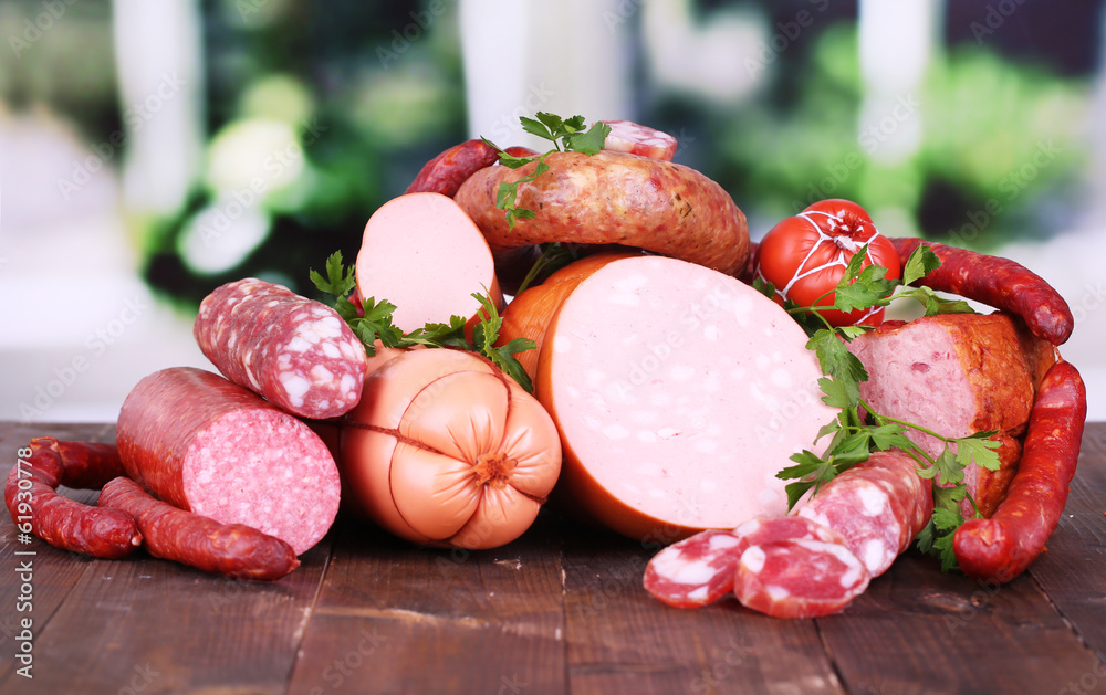 Lot of different sausages on wooden table on window background