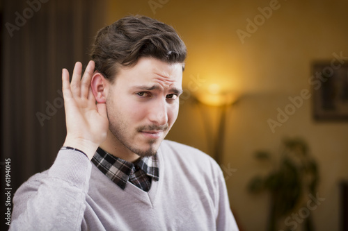 Foto Handsome young man can't hear, putting hand around his ear