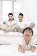 © eastfenceimage - .Young Chinese girl in a living room with parents in the backgro