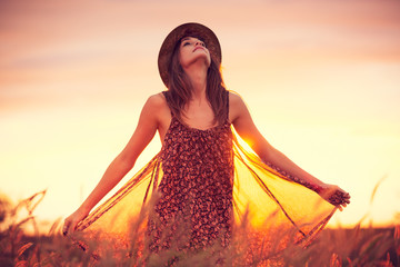 Beautiful woman in golden field at sunset