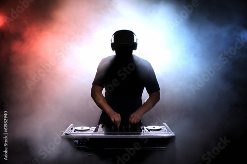 Fotografie, Obraz Disc jokey silhouette over illuminated smoke background