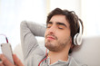 Young relaxed man listenning music in the sofa