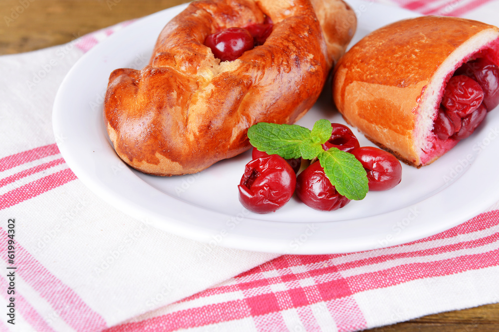 Fresh baked pasties with cherry on plate on table close-up