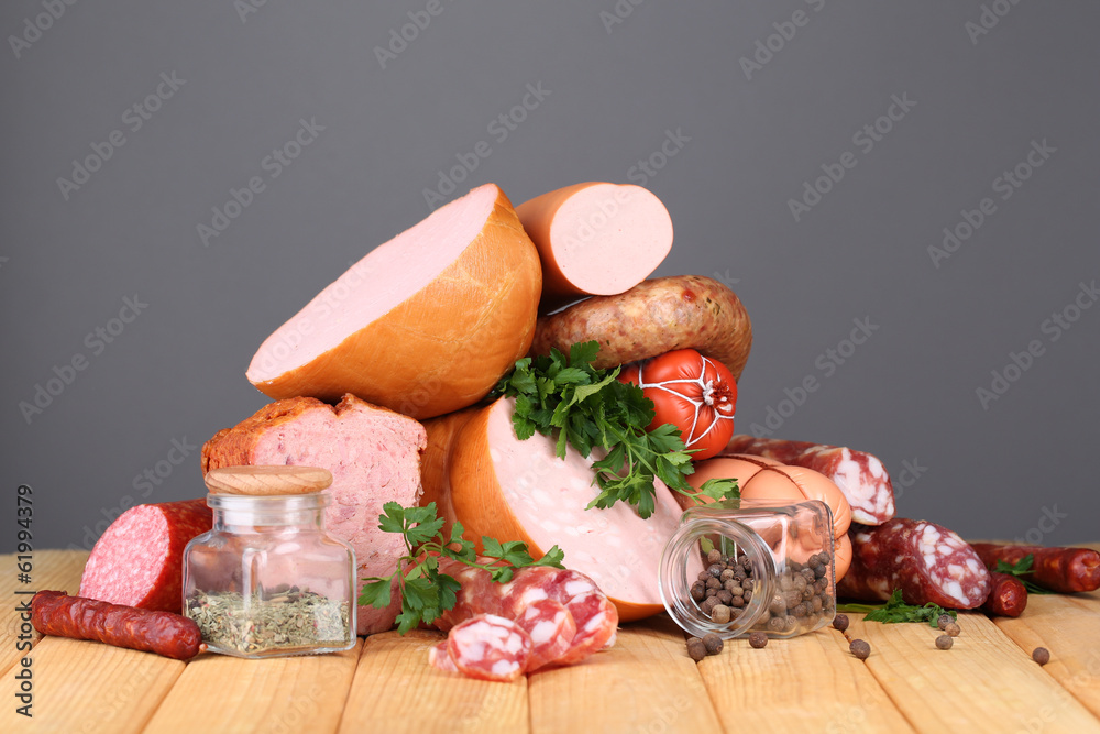 Lot of different sausages on wooden table on grey background