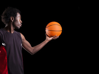 Wall Mural - Portrait of a basketball player holding a ball against dark back