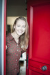 © jackfrog - beautiful young woman opening a red door to welcome someone