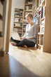 © jackfrog - young student sit on the floor working on her computer near fami