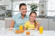 © lightwavemedia - Mother and daughter sitting at breakfast table