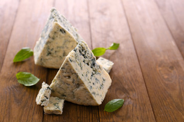 Tasty blue cheese with basil, on wooden table