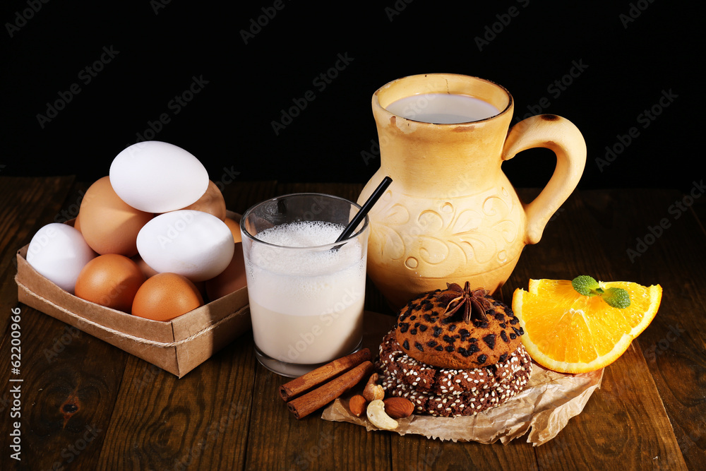 Eggnog with milk and eggs on table and black background