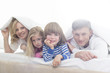 © MDBPIXS - Portrait of happy parents and children lying under bed cover