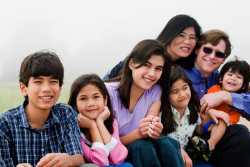 Multiracial family of seven sitting on beach