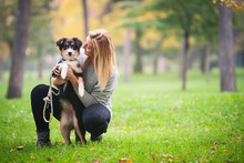 Young Woman Playing With Australian Shepherd Dog Outdoors In The