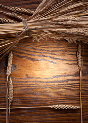 Canvas Print - Ears of wheat on old wooden table.