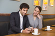 © ldprod - Young couple using a smartphone in restaurant