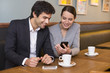 © ldprod - Young couple using a smartphone in restaurant