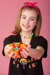 Wall Mural - Young girl with a handful of colorful candy