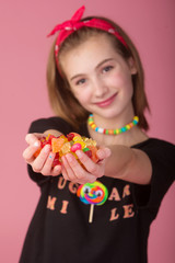 Wall Mural - Young girl with a handful of colorful candy