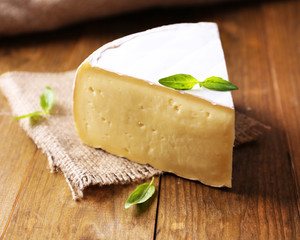 Canvas Print - Tasty Camembert cheese with basil, on wooden table