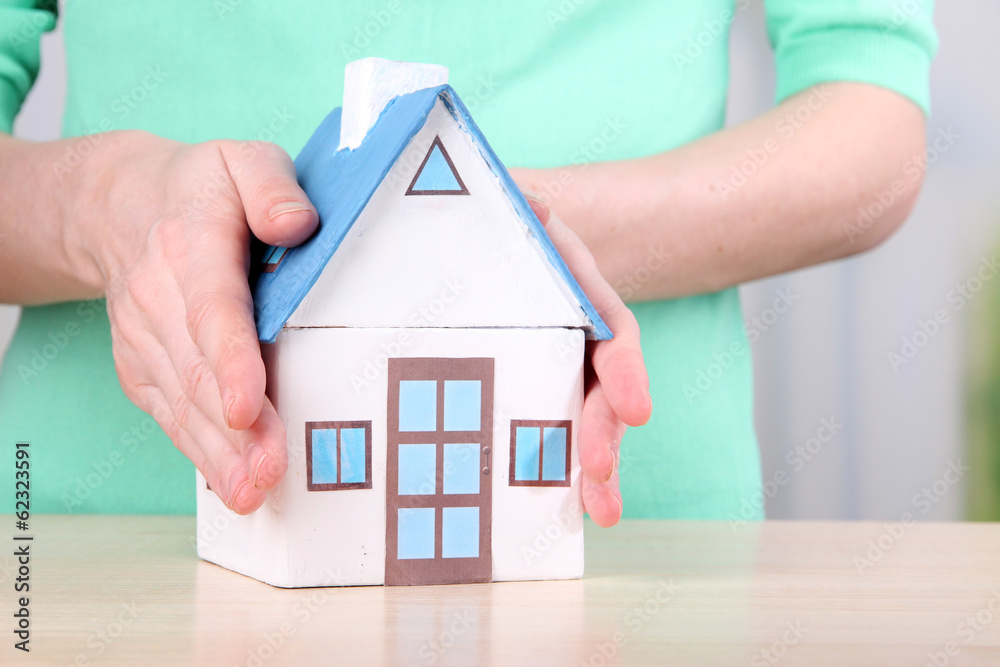 Little paper house in hand close-up, on light background