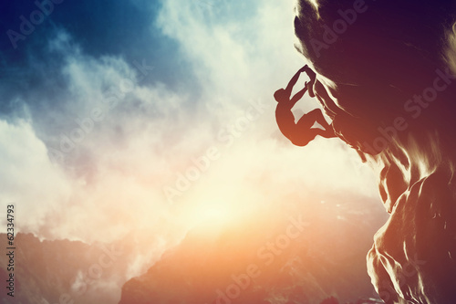Fotografie, Obraz A silhouette of man climbing on rock, mountain at sunset.