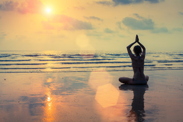 Wall Mural - Silhouette of a woman yoga on sea sunset.