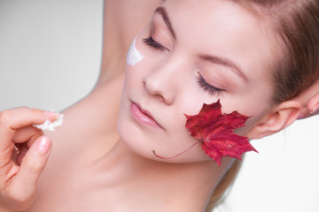 Skin care. Face of young woman girl with red maple leaf.