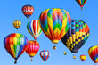 Colorful hot air balloons flying against clear blue sky, ballooning fiesta