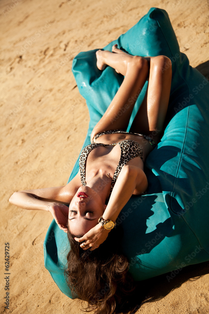 Beautiful young seductive sexy brunette lying on the beach - obrazy, fototapety, plakaty 