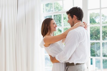 Wall Mural - Side view of loving couple embracing at home
