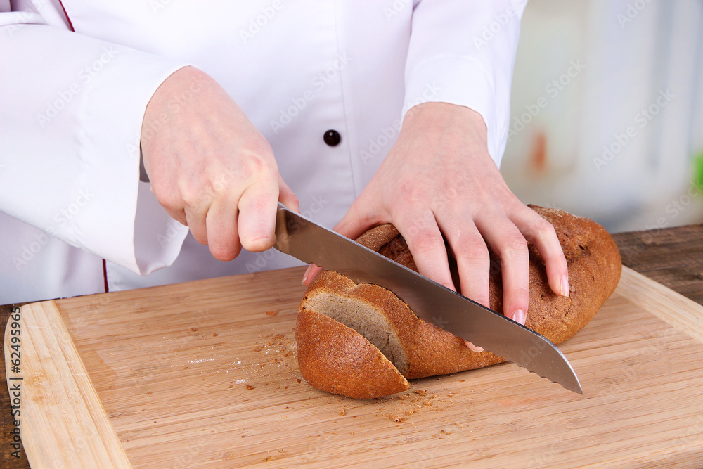 Cutting bread on wooden board on bright background