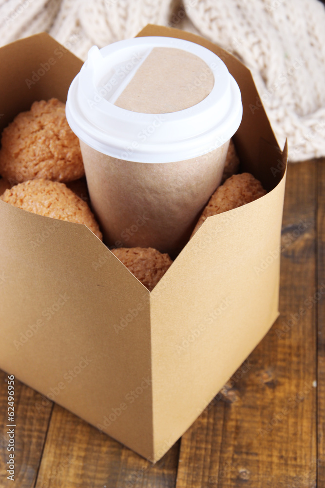 Hot coffee and cookies in box on wooden table close-up