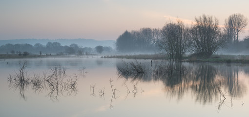 Wall Mural - landscape of lake in mist with sun glow at sunrise