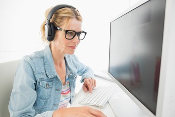 Wall Mural - Blonde designer wearing headphones working at computer