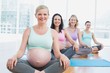 © WavebreakmediaMicro - Happy pregnant women in yoga class sitting on mats