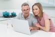 © lightwavemedia - Concentrated couple using laptop in kitchen