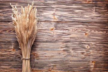 Canvas Print - Ears of wheat on old wooden table.