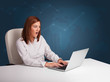 © ra2 studio - Young woman sitting at desk and typing on laptop